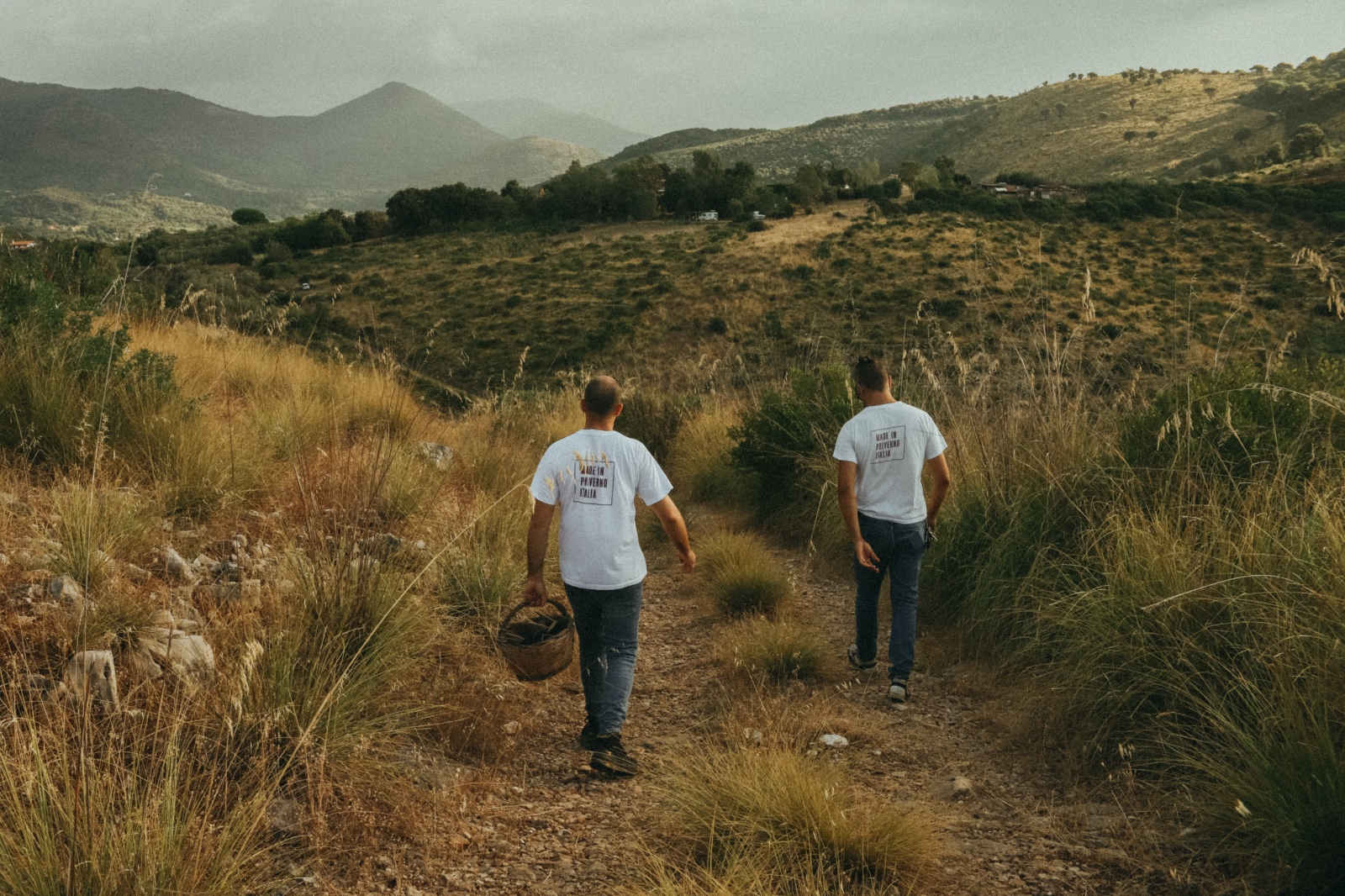 Due figure che camminano lungo un sentiero nella campagna laziale